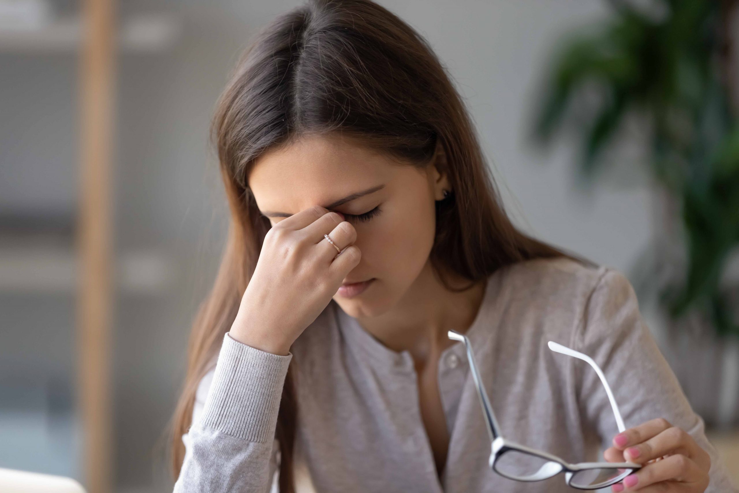 Close up portrait of young unhealthy woman taking off eyeglasses suffers eye strain tension massaging nose bridge, concept of poor vision caused by long time usage electronic devices computer overuse