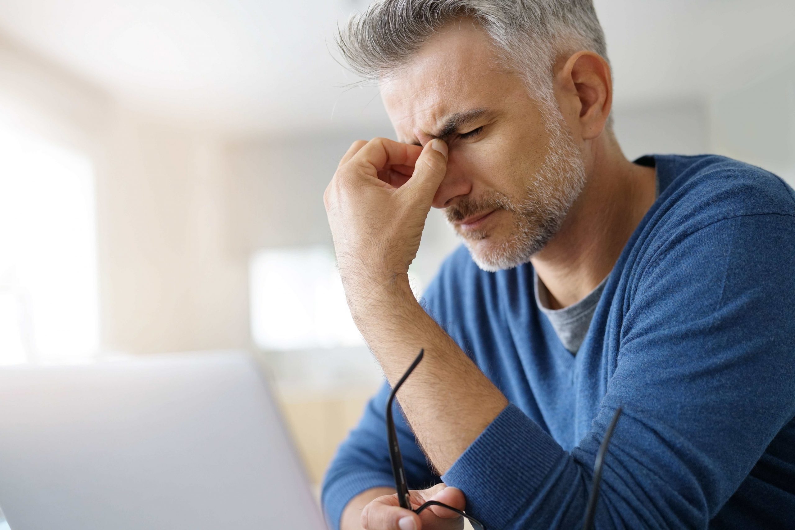Man at home having a headache in front of laptop Man at home having a headache in front of laptop