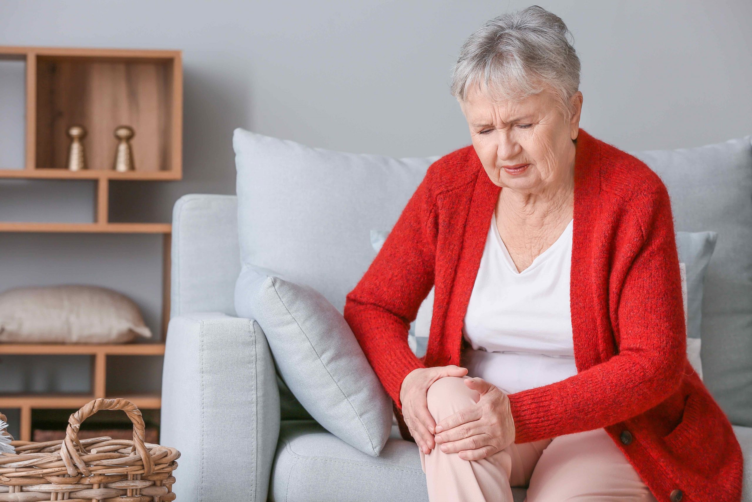 Senior woman suffering from pain in knee at home Senior woman suffering from pain in knee at home