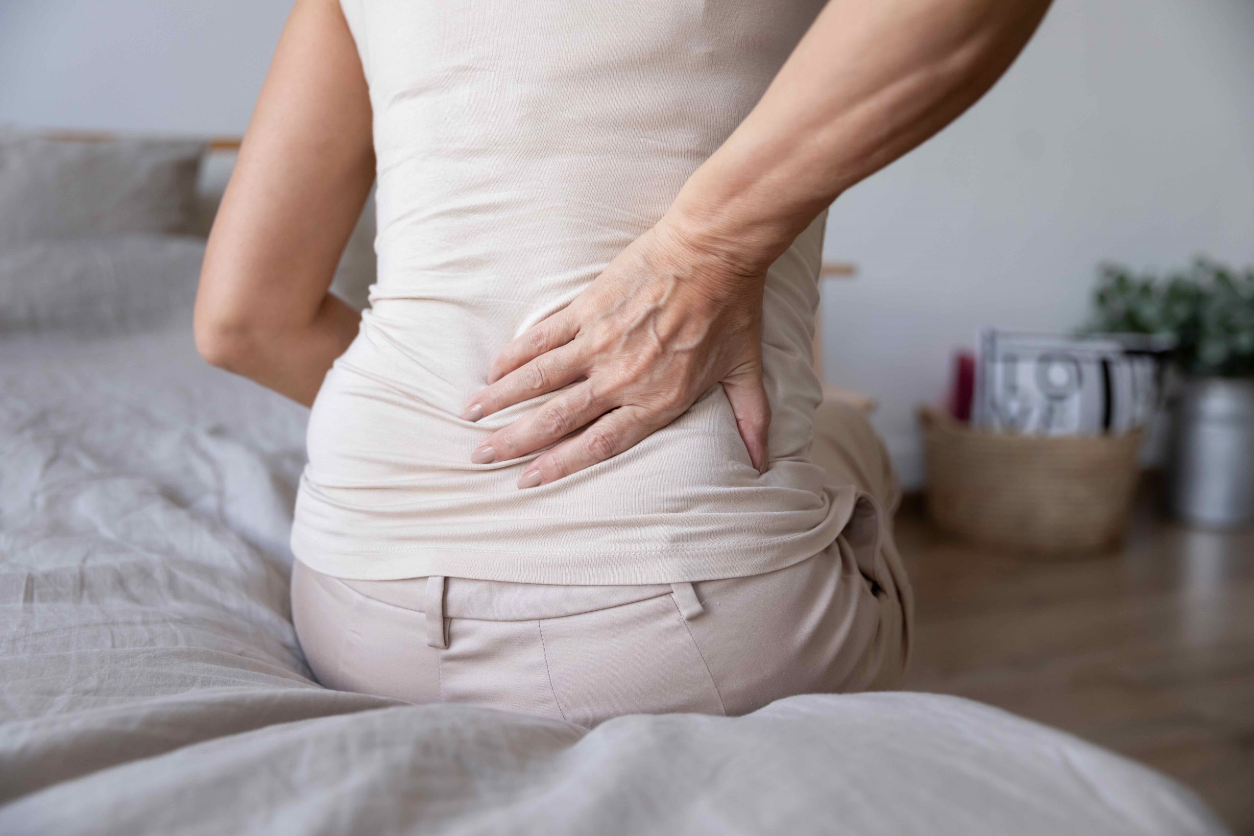 Old mature woman sit on bed touch back feel backpain Old mature woman sit on bed touch back feel morning backpain suffer from lower lumbar discomfort muscle pain wake up with backache after sleep on uncomfortable mattress concept, close up rear view