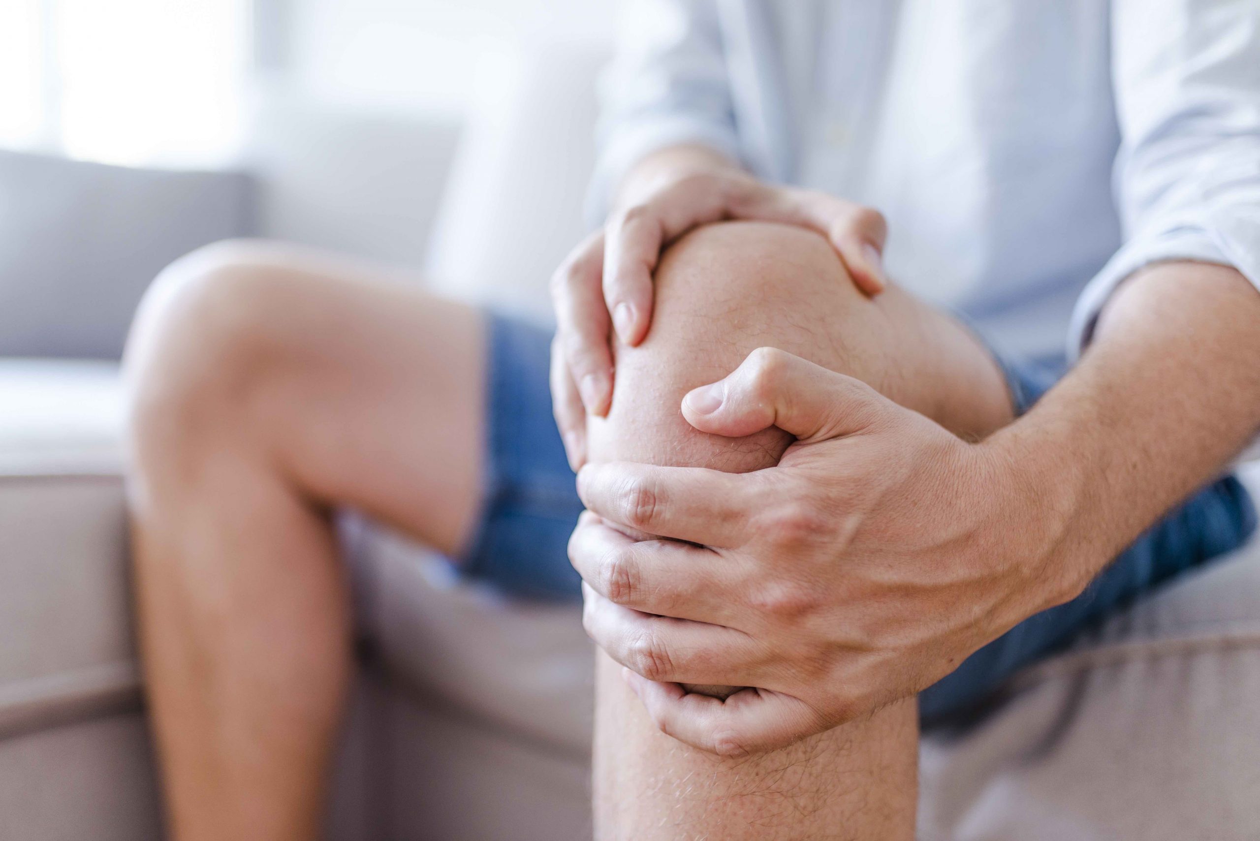 Man suffering from knee pain sitting sofa knee pain stem cell therapy